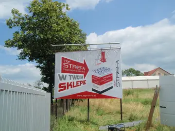 Tablica reklamowa na konstrukcji stalowej przy ogrodzeniu