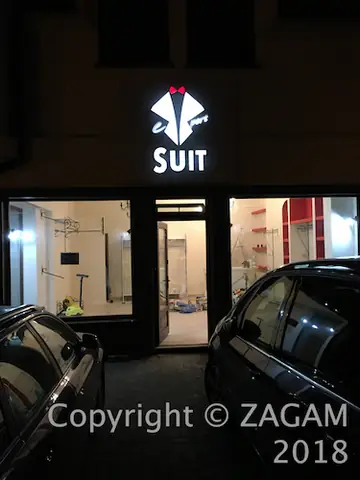 Podświetlany szyld SUIT nad wejściem nocą