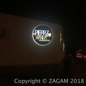 Okrągły podświetlany szyld Pieprz i Wanilia na ścianie nocą